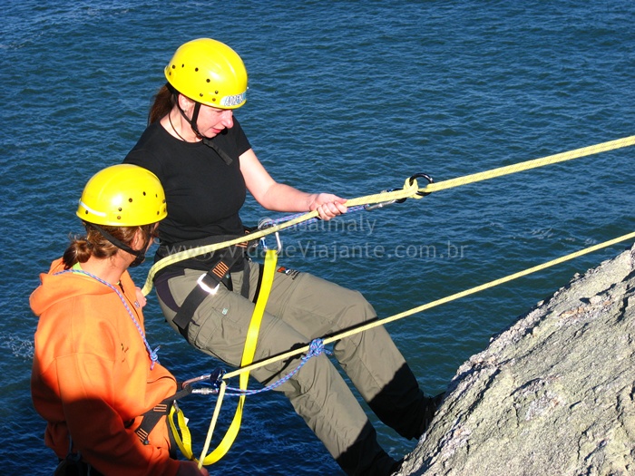 two people with yellow helmets and ropes climbing up cliffs