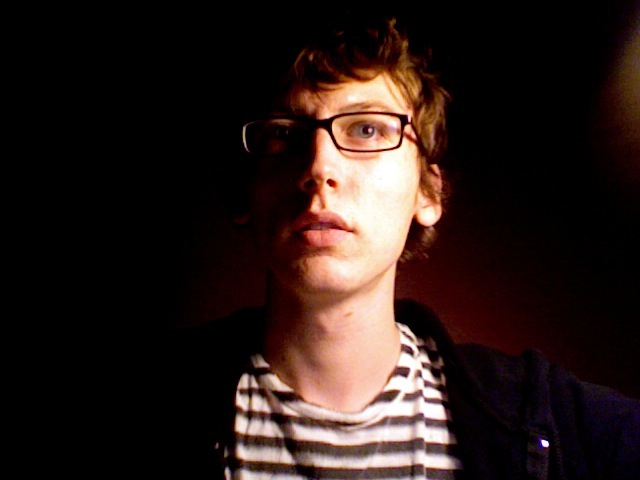 a young man wearing glasses and a shirt looking upward