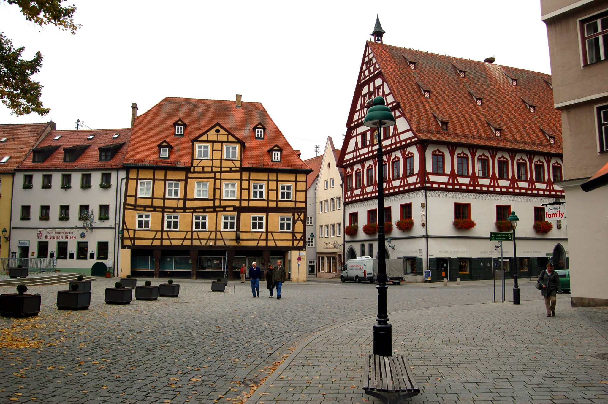 three people walking around a city with cobblestone sidewalks