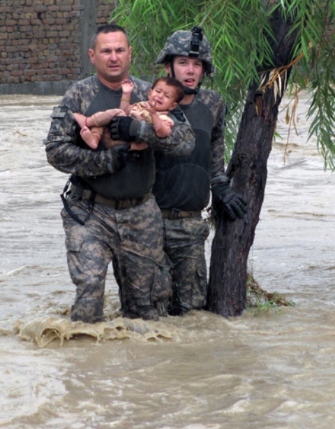 three men stand in a flooded area near a tree