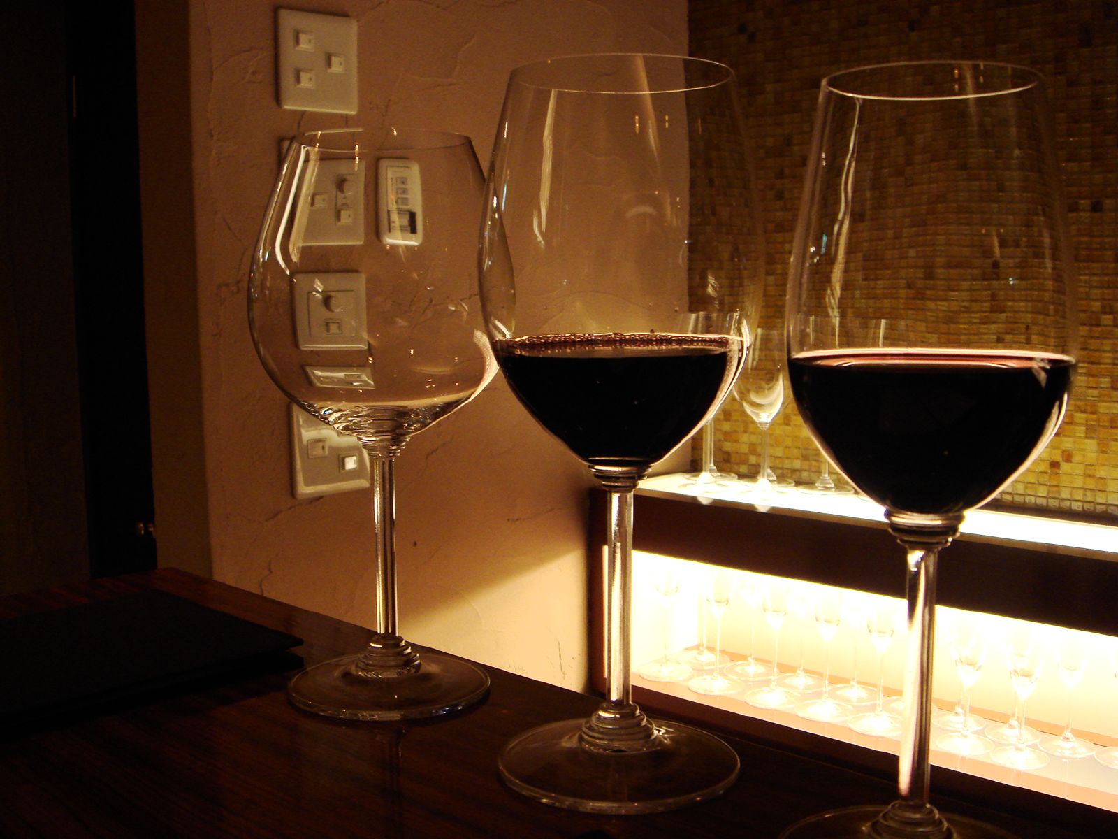 three glasses of wine sit on a table in the dark