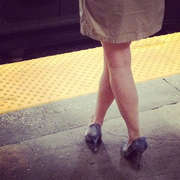 the women's shoes are on the sidewalk while they wait for the train