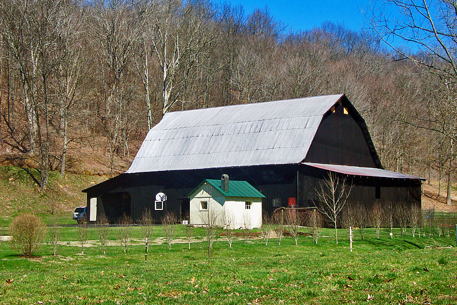 a large barn sits in a green grassy area