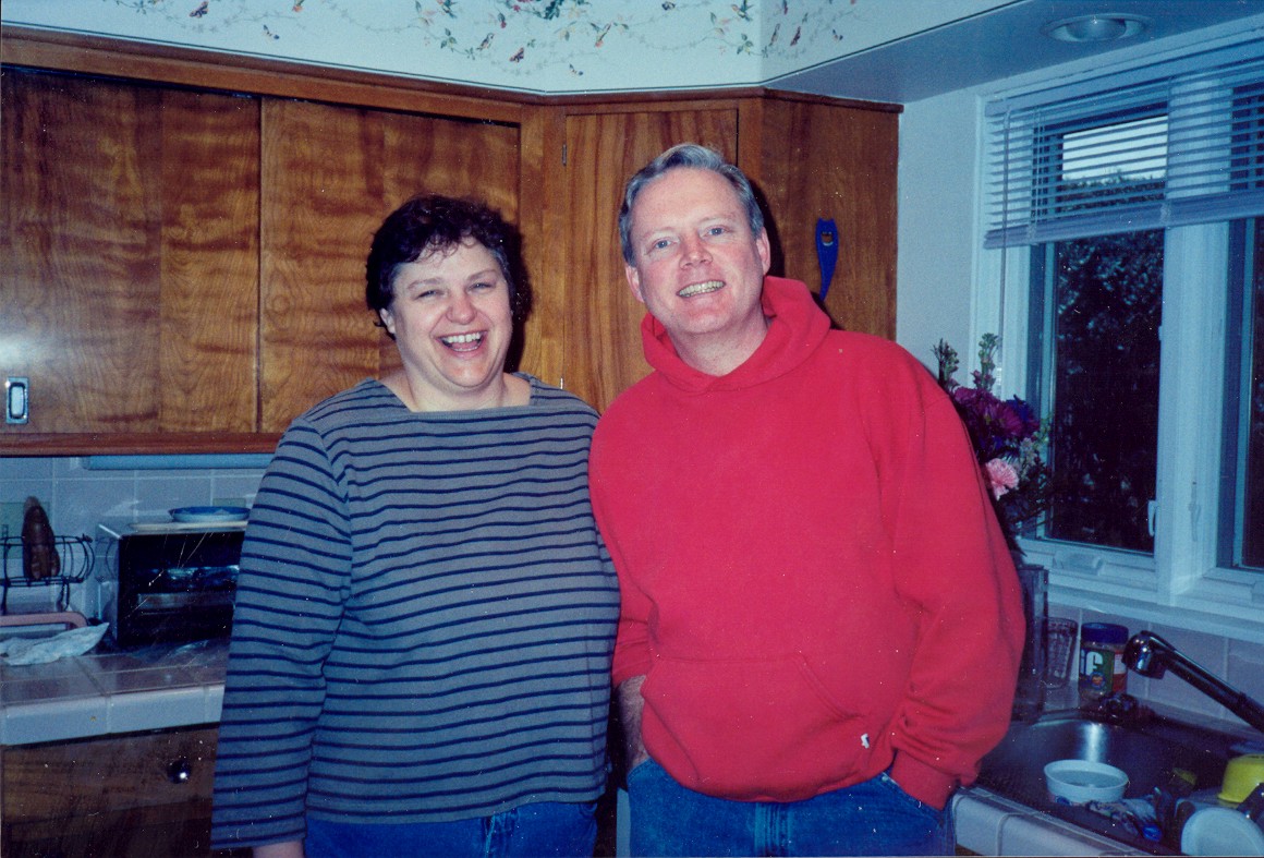 an older couple is posing for a picture in a kitchen