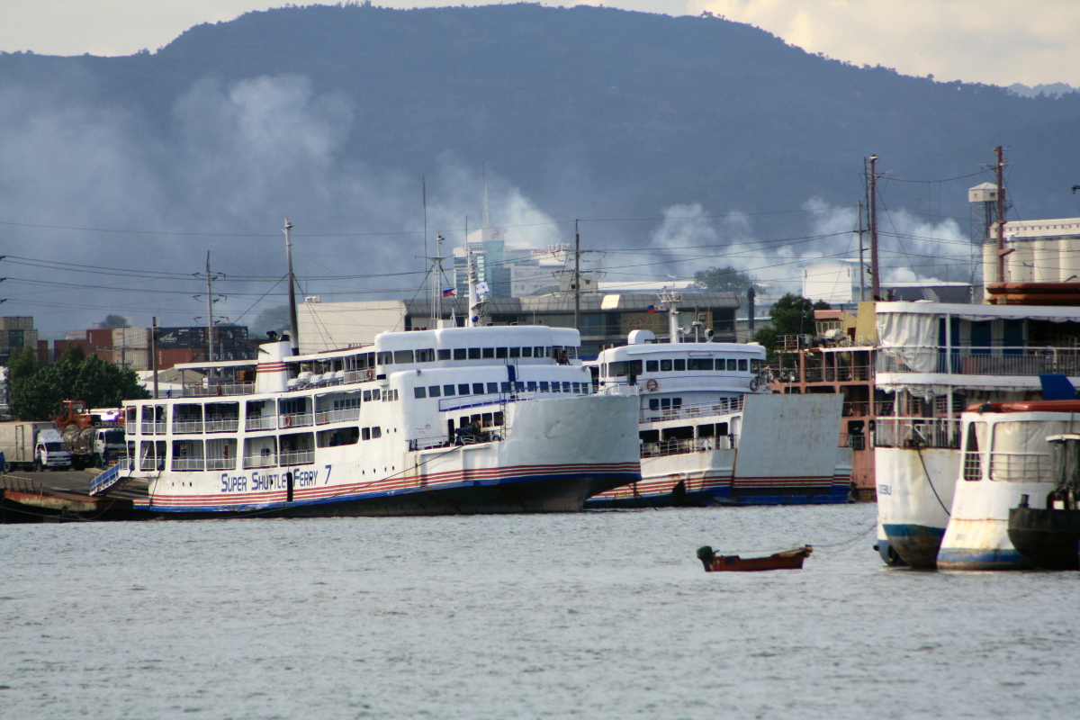 a ship parked in the water near some smaller boats