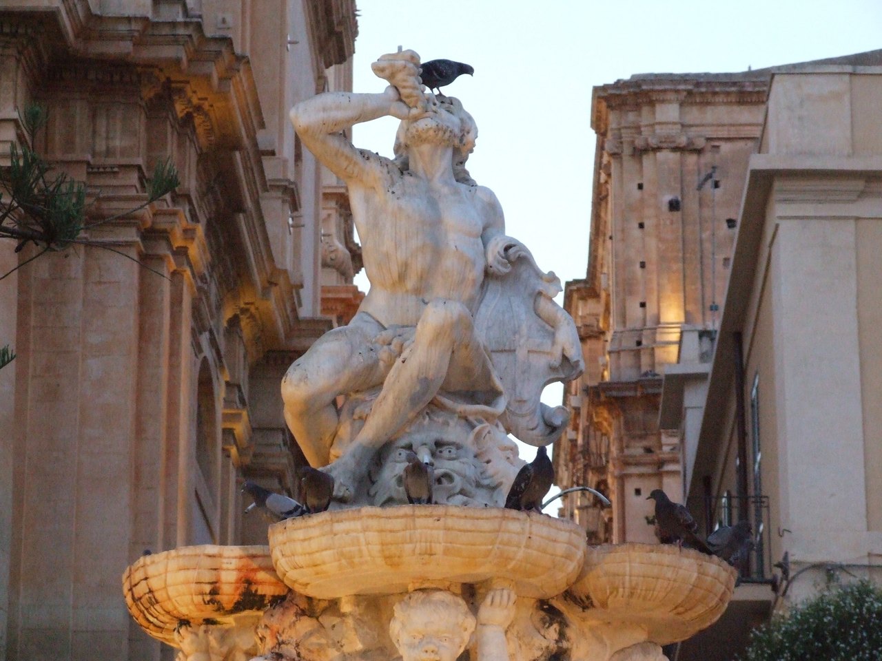 the fountain has birds perched on it next to a building