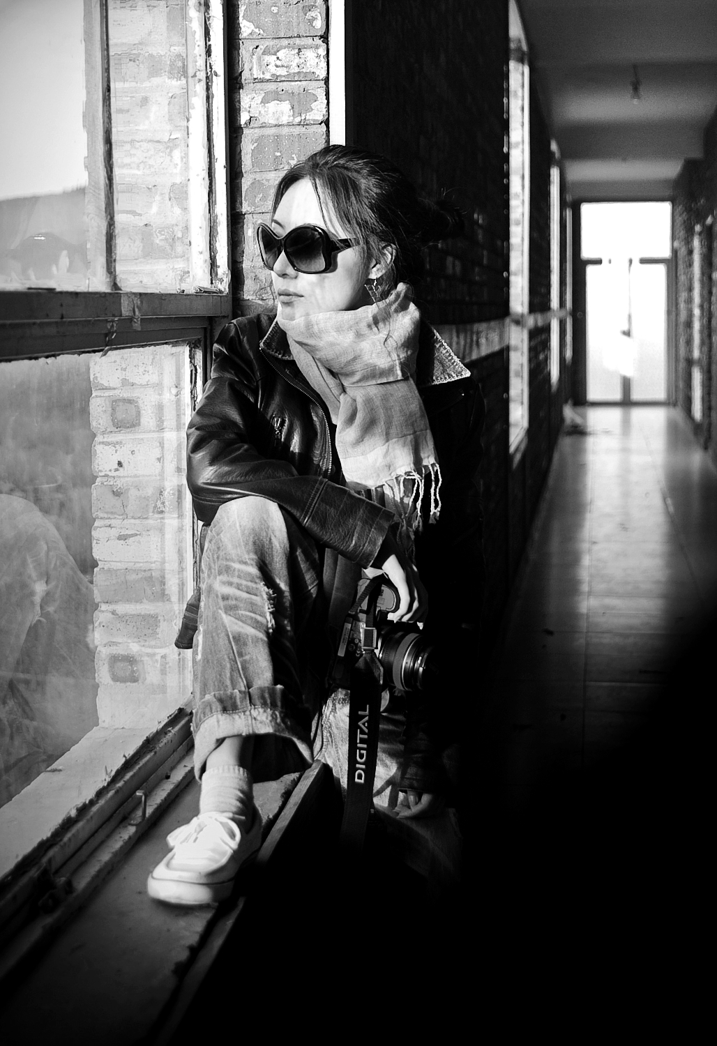 a woman in sunglasses and a scarf is sitting on a bench