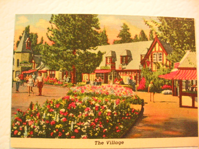 a postcard shows a village, flowers and people walking down a path