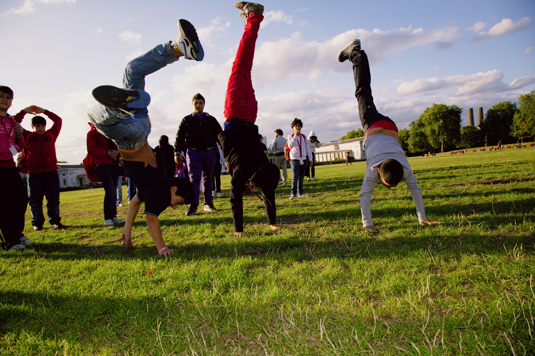 a group of s doing various poses with one in the air and another upside down in the ground