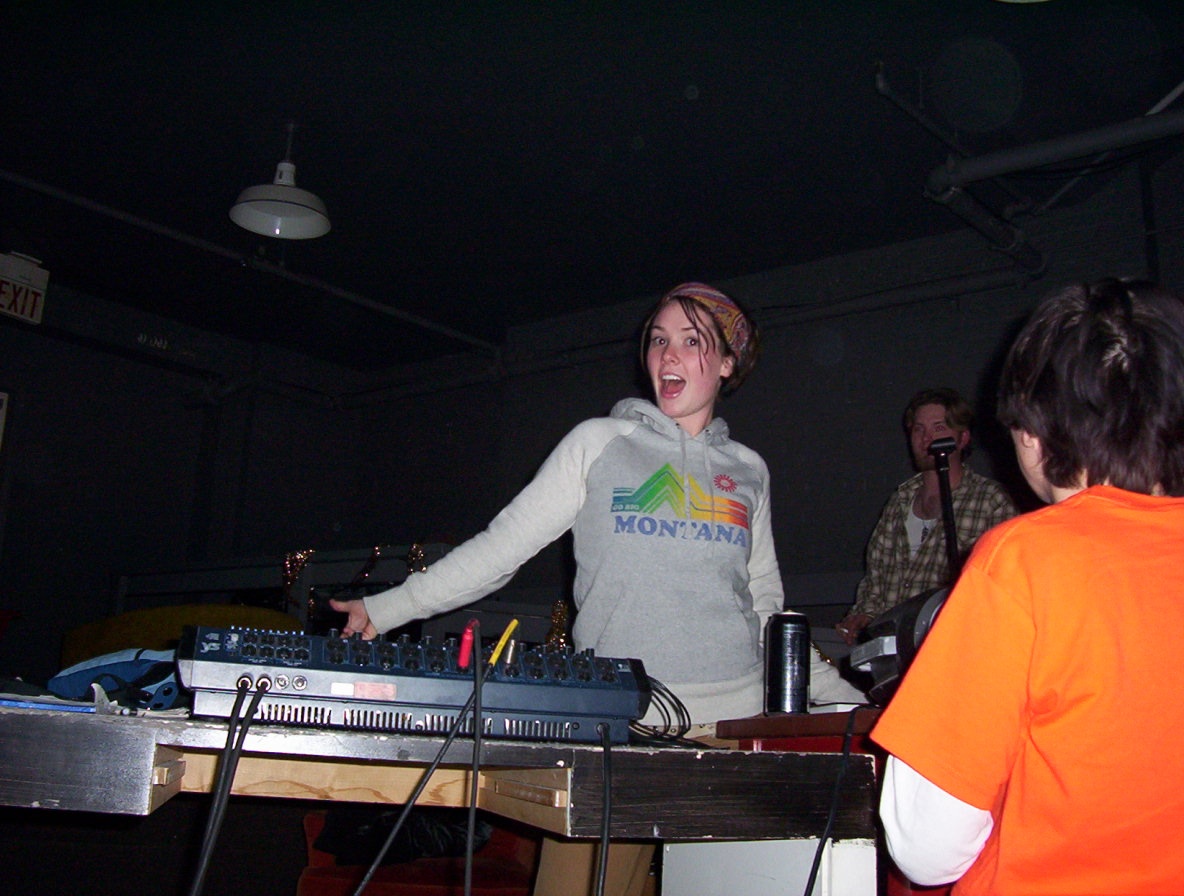 woman playing the dj with other people looking on