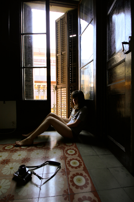 a woman sits on a bed while looking out the window