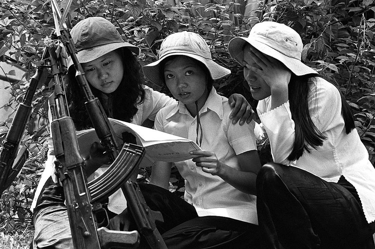 three asian girls sitting by a tree and writing
