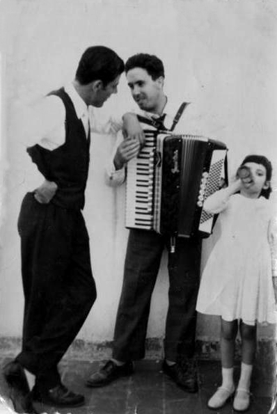 there are two adults and a child playing an accordion