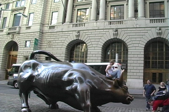 a boy on top of a bronze bull statue