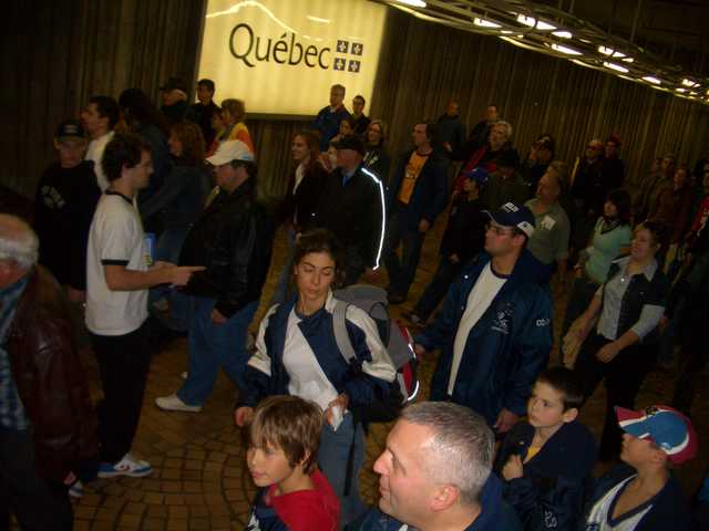 several people are standing in the hall, many have jackets