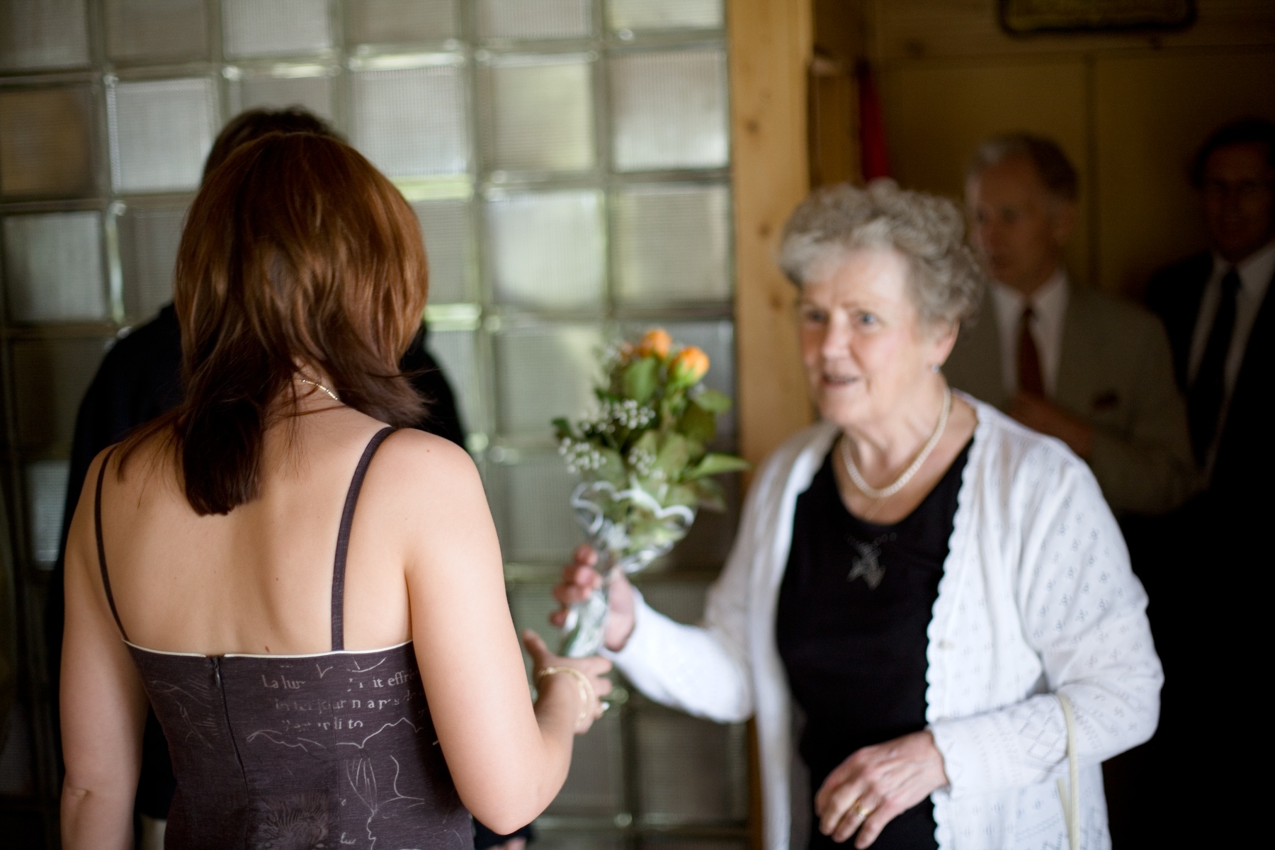 an old lady looking in another woman's hand and holding a flower