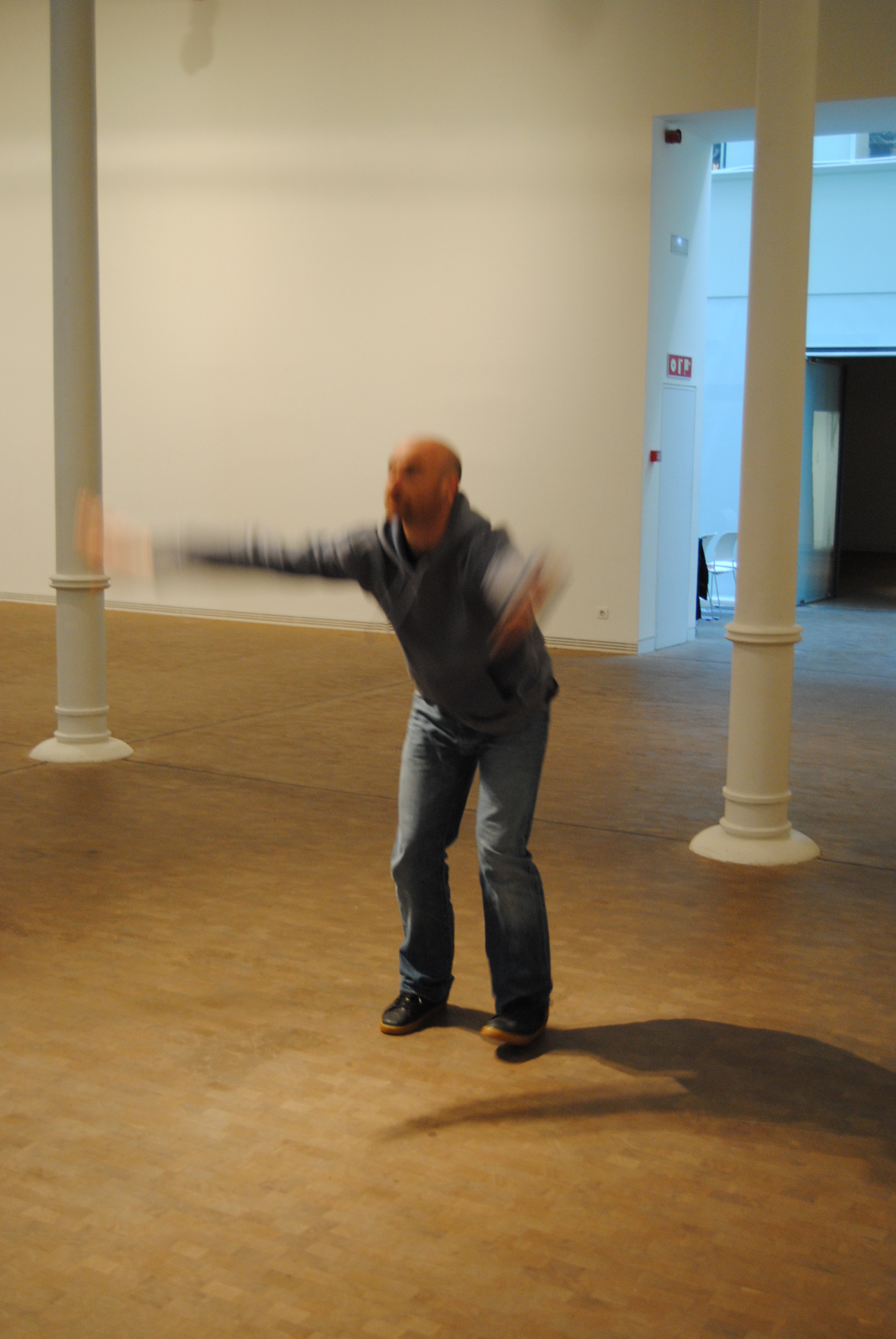 man in grey sweater throwing a flying disc in a large building