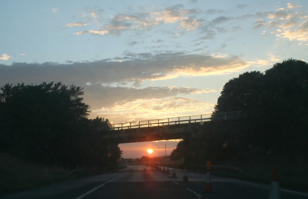 the sun setting in front of a bridge