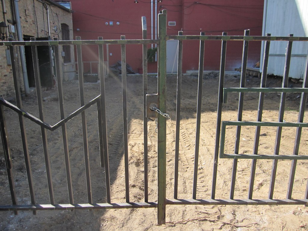 some metal gates near a building and dirt