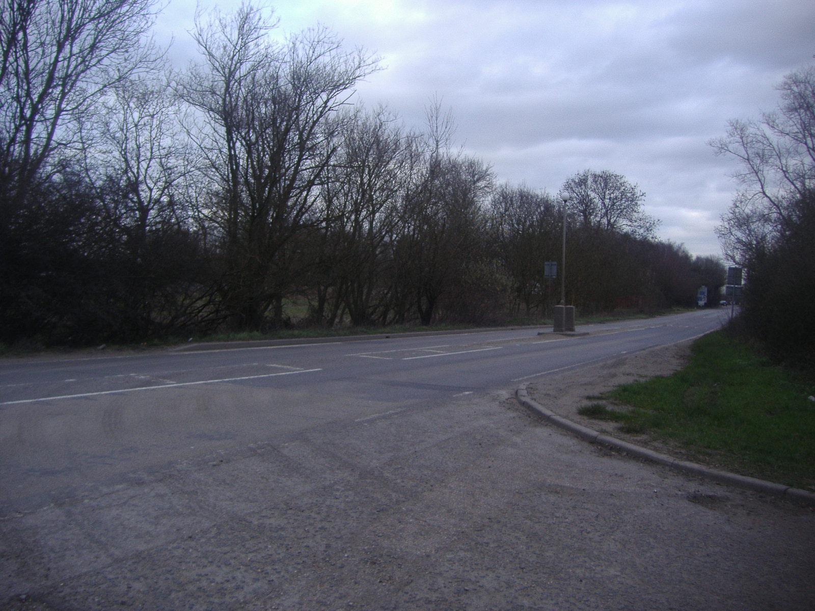 the side of an empty road with a parking meter near it