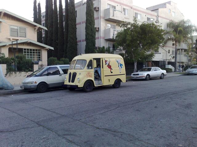 a mini bus with the door opened sitting next to a car