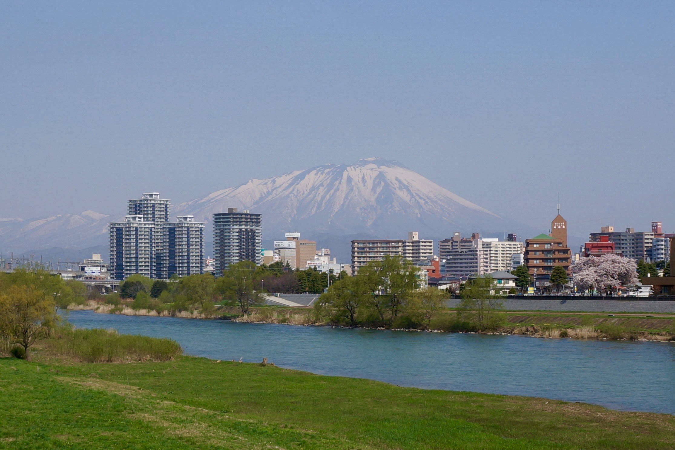 there is a view of the city from a grassy hill near water