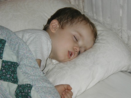 a young child asleep with his eyes closed while wrapped up in a blanket