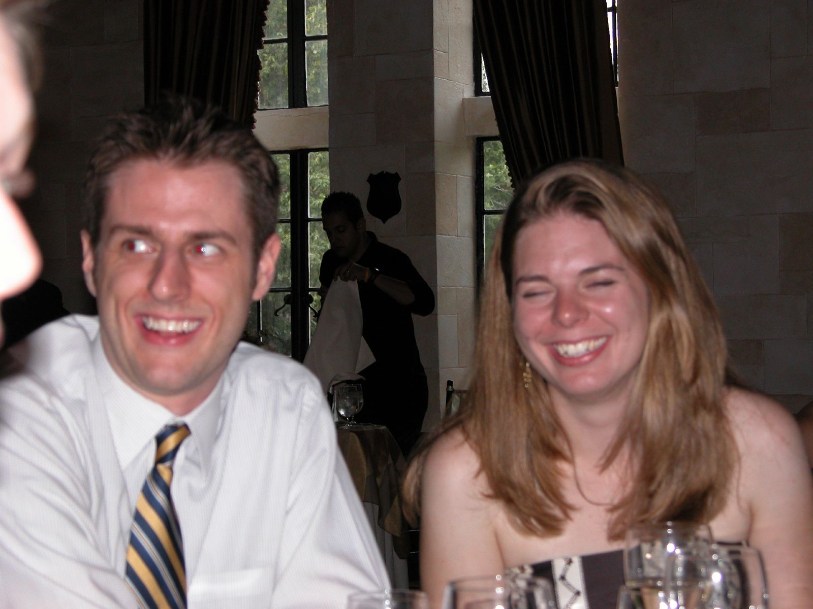 two people smiling and laughing while sitting at a table