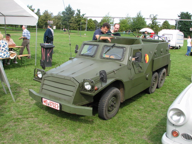 people admiring the unusual military vehicle with two men in it