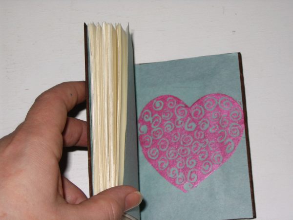 a person's hand holding a book with a design on it