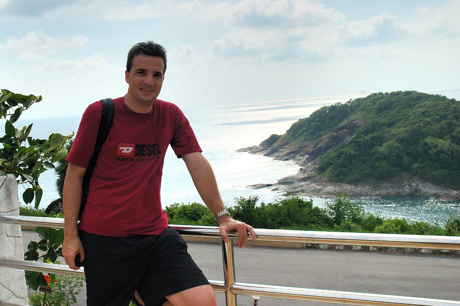 a man stands near a railing holding his skateboard