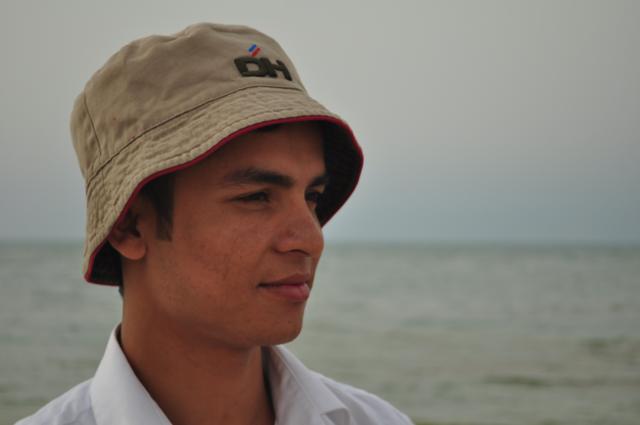 man with hat looking at camera at ocean