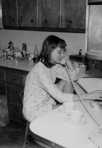 a woman in pajamas on phone next to sink