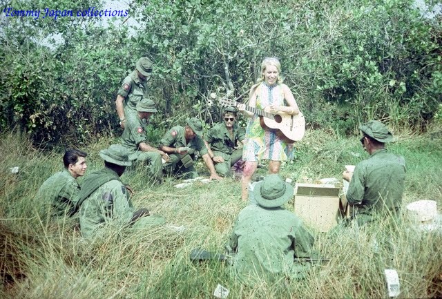 a woman is playing guitar in a field