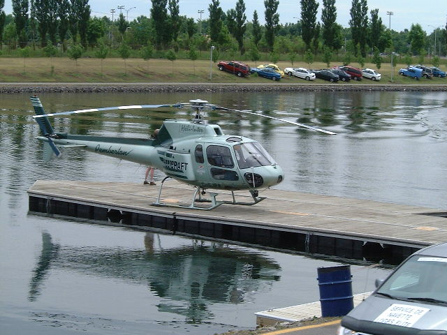 a helicopter is sitting on a dock next to cars