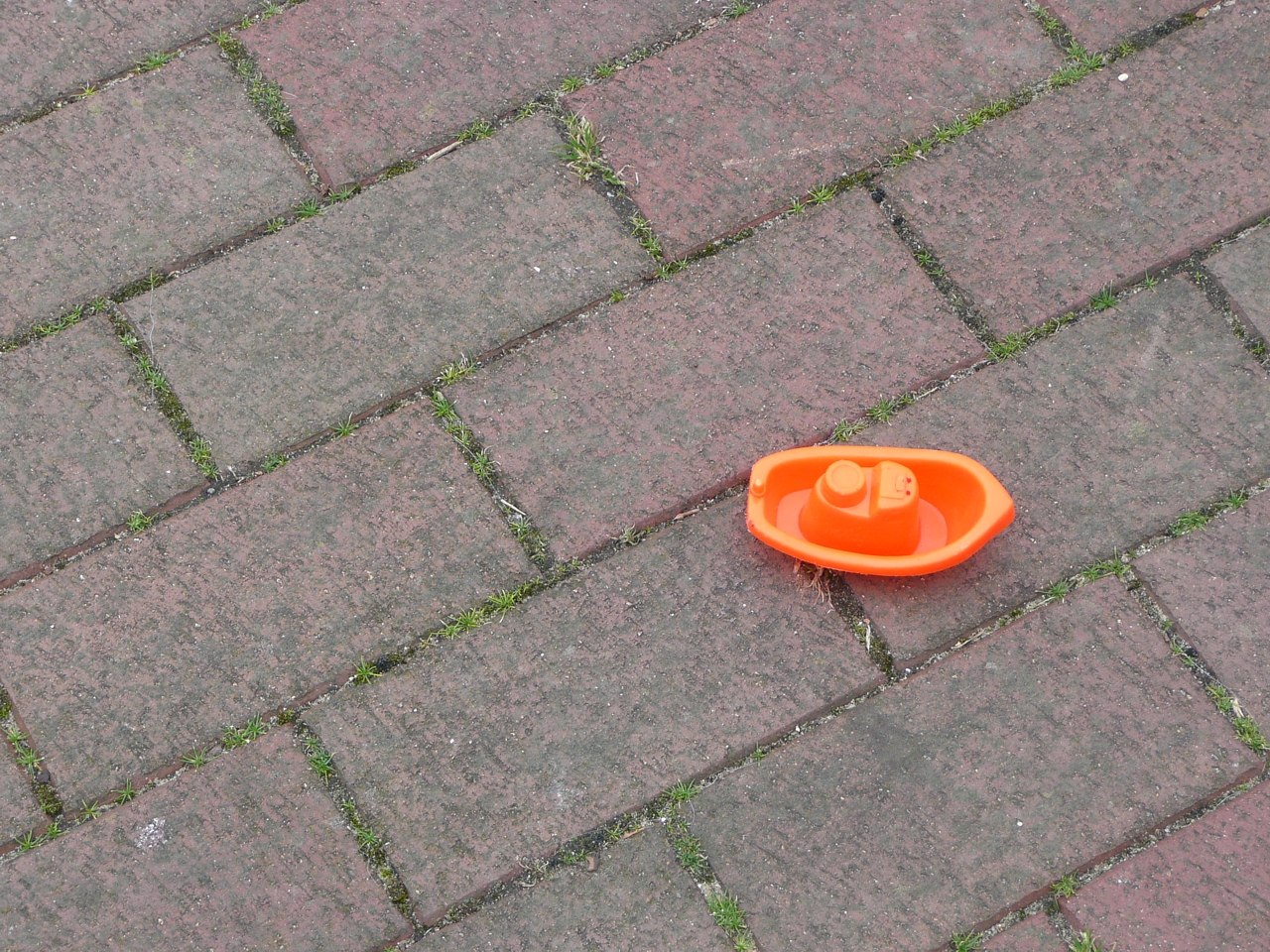 an orange and white cone is on a brick walkway