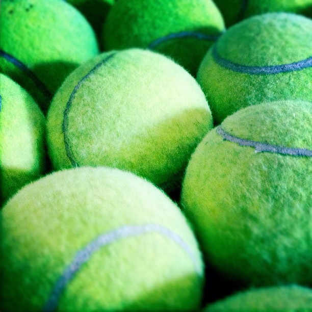 a group of tennis balls filled up with green tennis balls