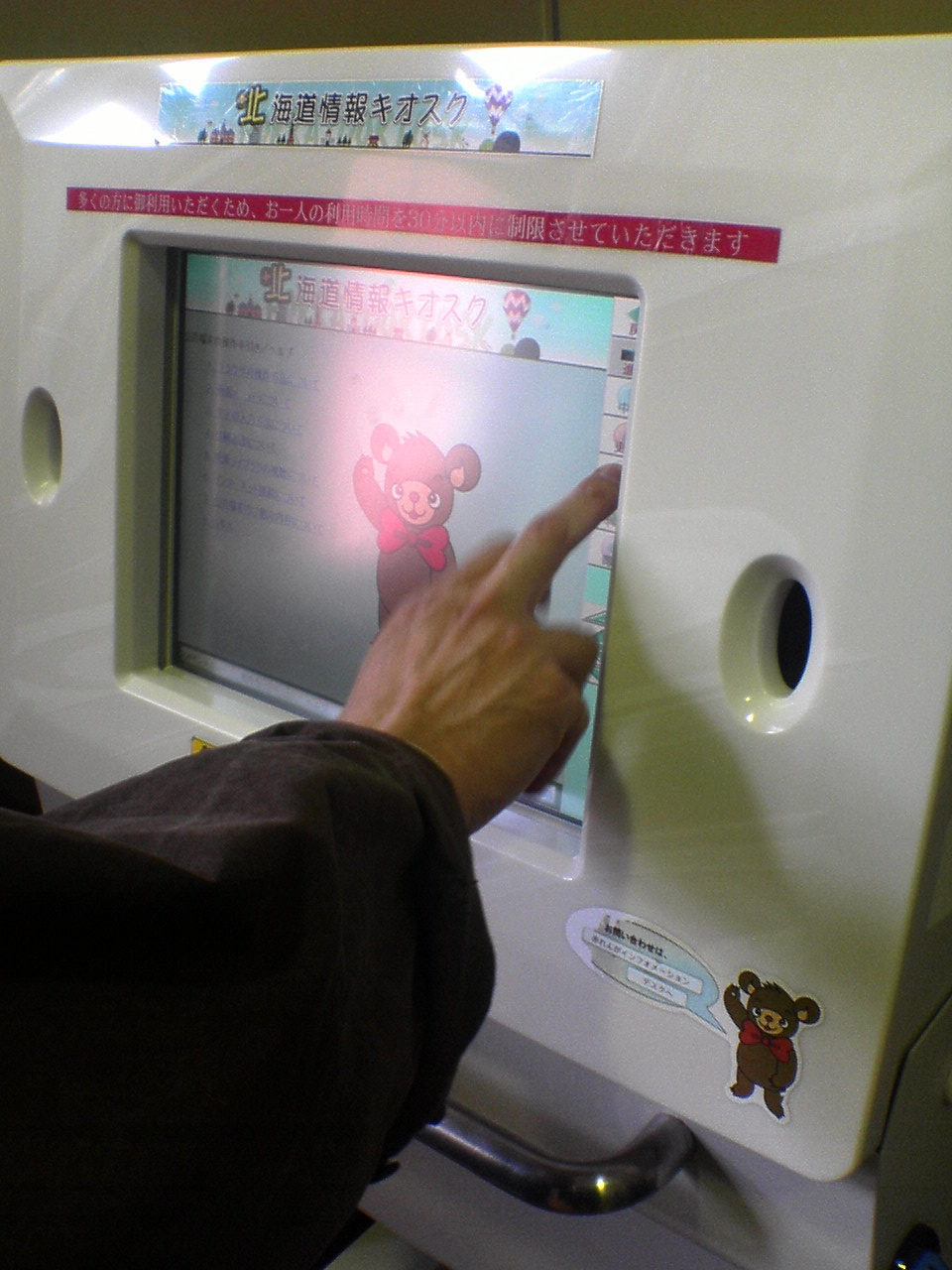 the hand is pointing to the screen in front of a bear