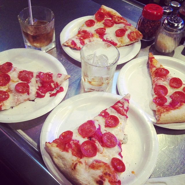 several plates have slices of pizza and beverages