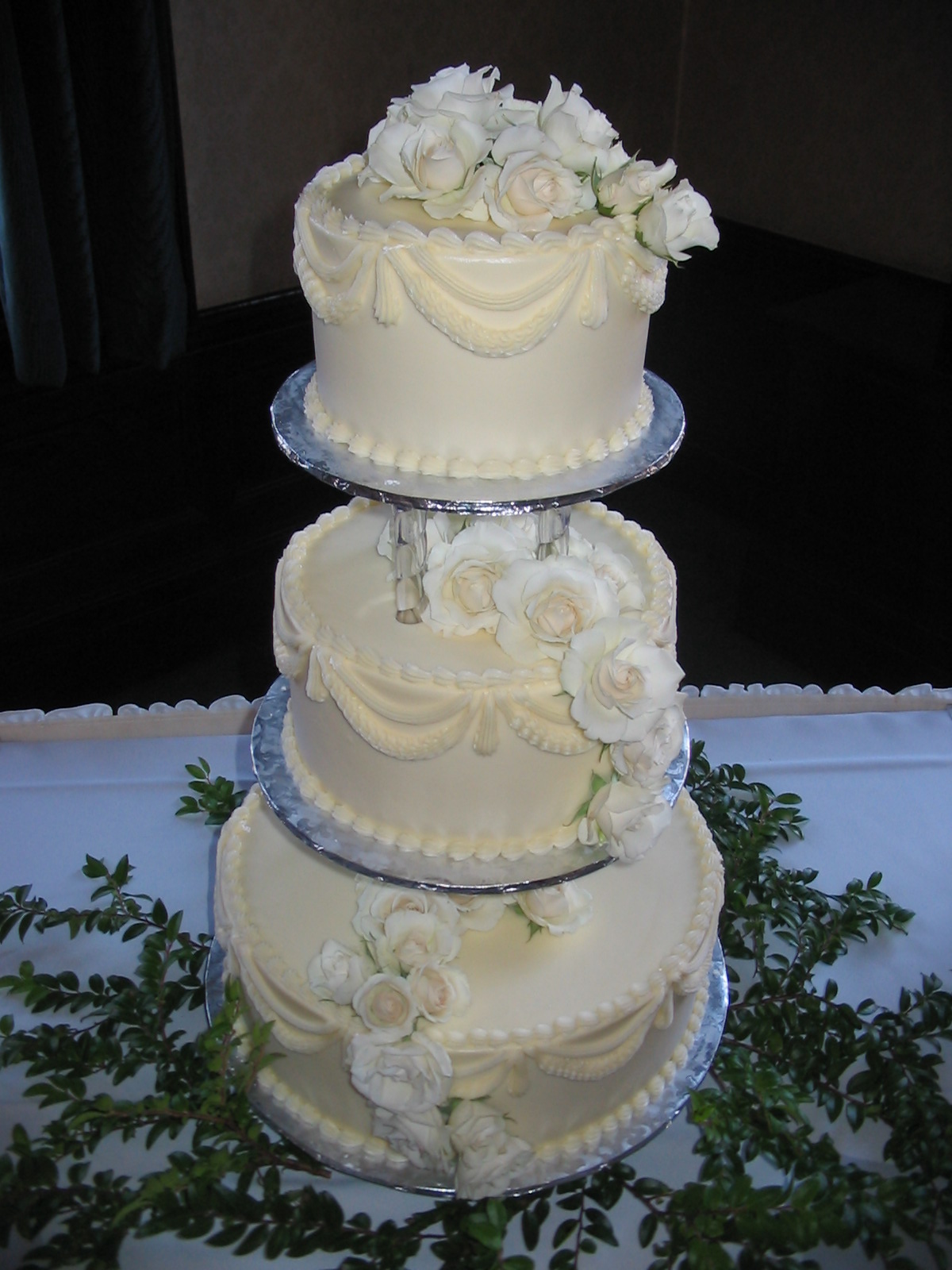 a three tier wedding cake with white roses on top