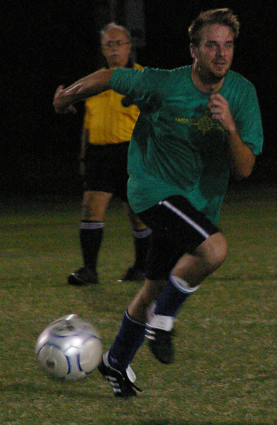 two men are running towards a soccer ball