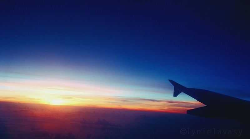the sunset seen through an airplane window with the wing visible