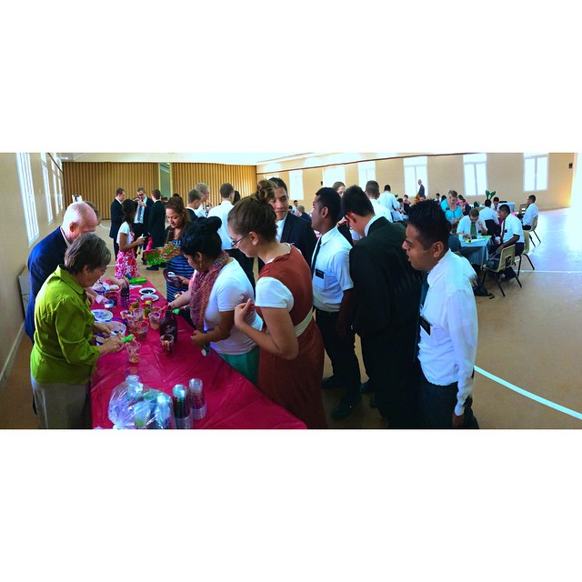 a group of people standing around a table filled with food