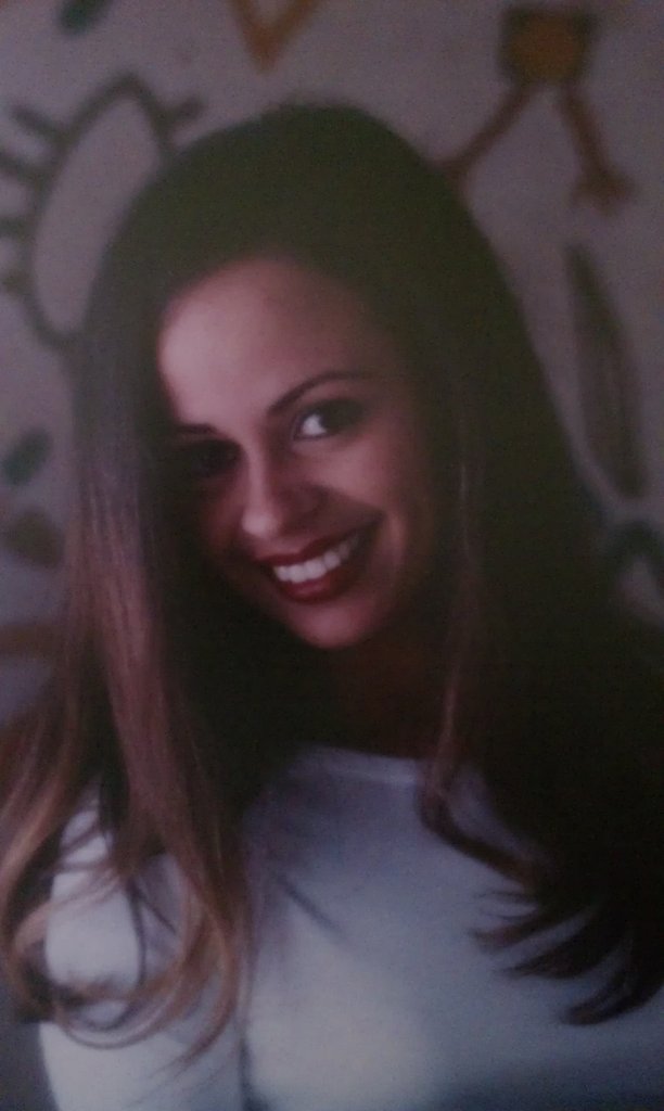 a smiling woman in white top near floral wall