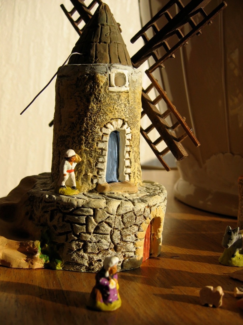 a doll house with a windmill and figurines on the table