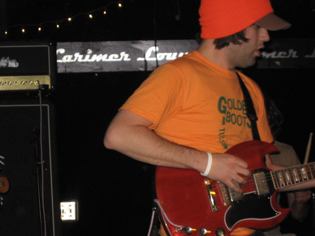the man in the orange hat is playing guitar