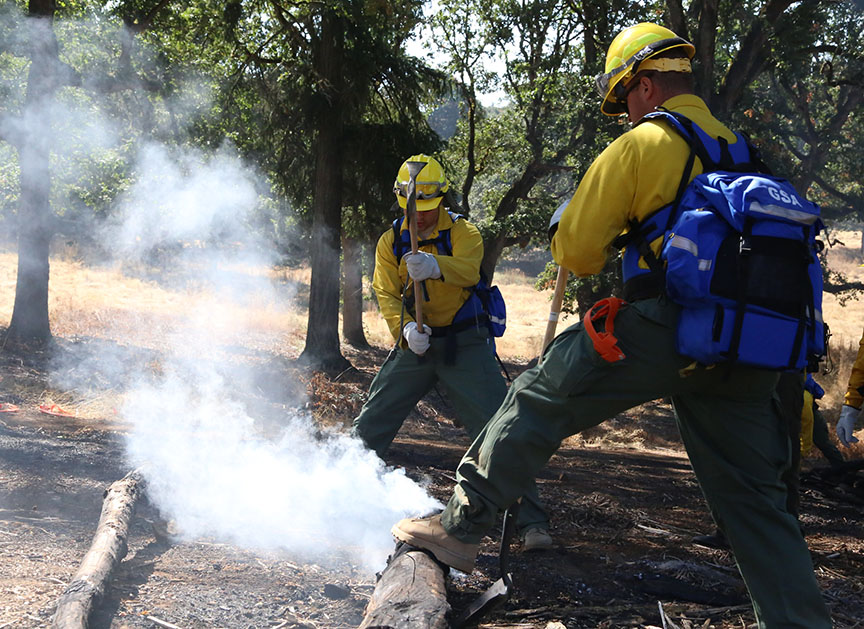 some people in helmets and vests by a fire