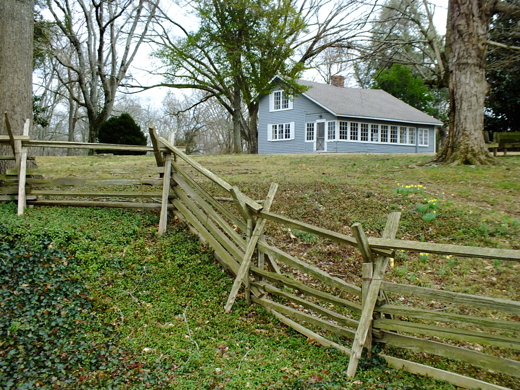 a large house sits in the distance behind a split fence