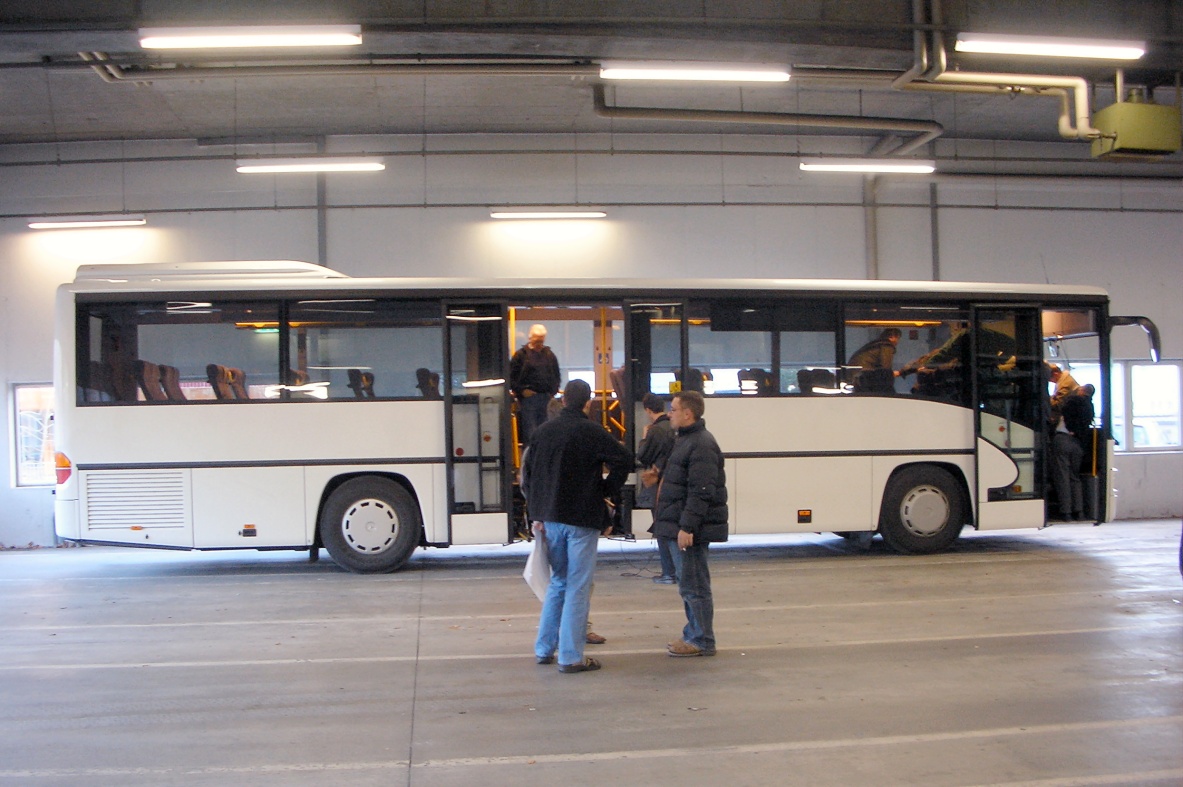 a large white bus parked inside of a parking garage