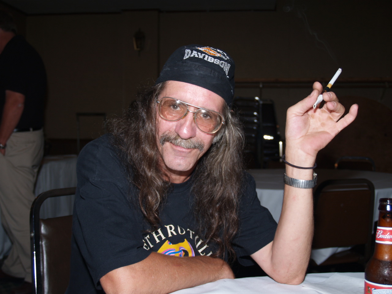 a man with a hat, shirt, and smoking cigarette